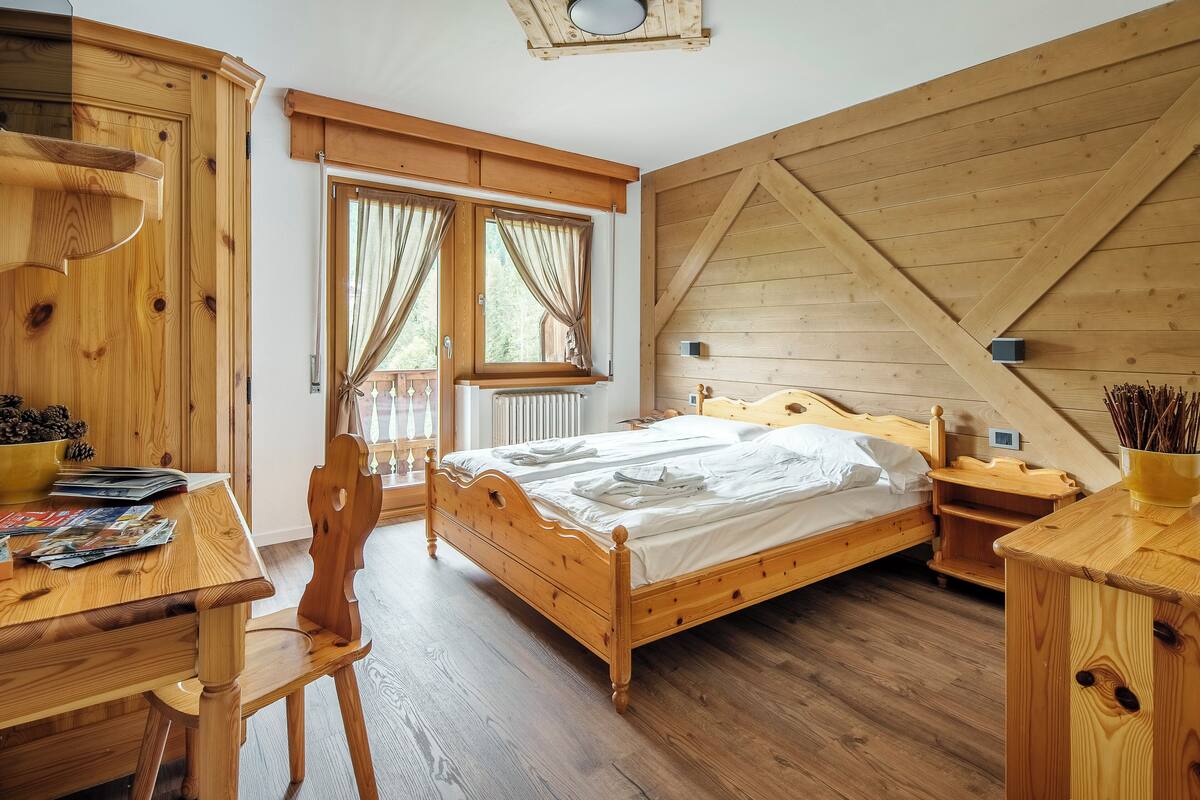 A wooden bedroom with a bed, a desk, and a chair.