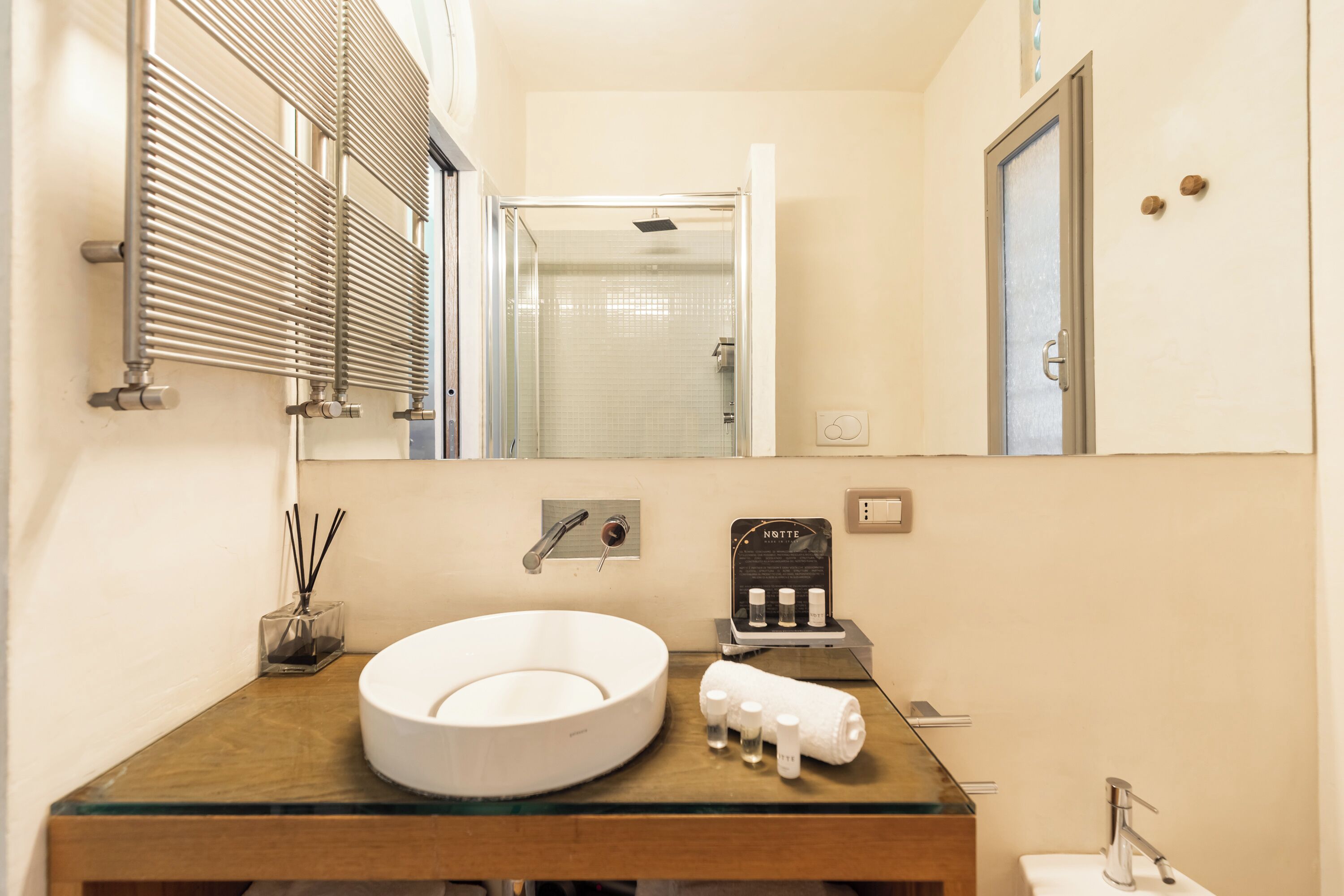 Une salle de bain avec un lavabo rond, un miroir, une serviette et un espace douche.