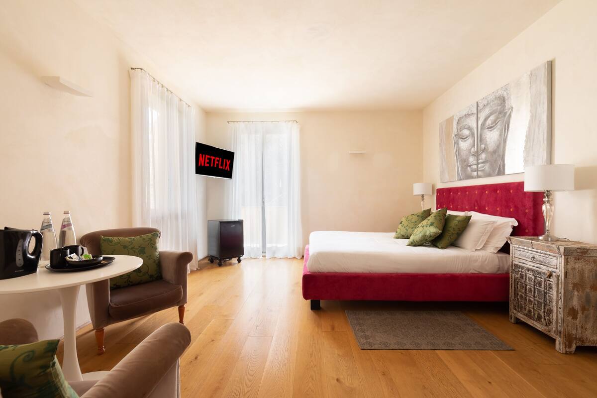 A hotel room with a bed, a desk, a chair, a TV, and a wall art piece.