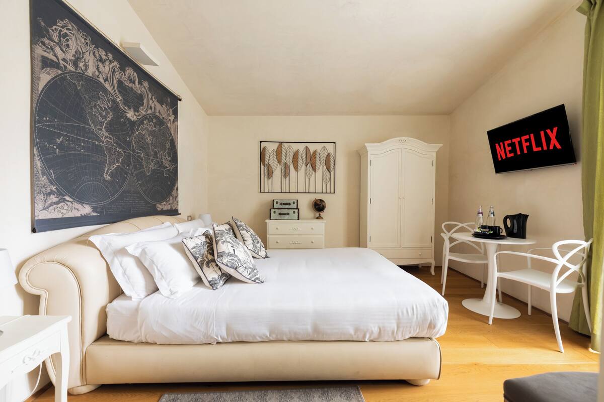 A bedroom with a bed, a map on the wall, a TV, a wardrobe, and a small table with chairs.