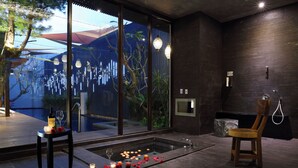 Een moderne badkamer met een groot raam, een bad en een houten stoel.