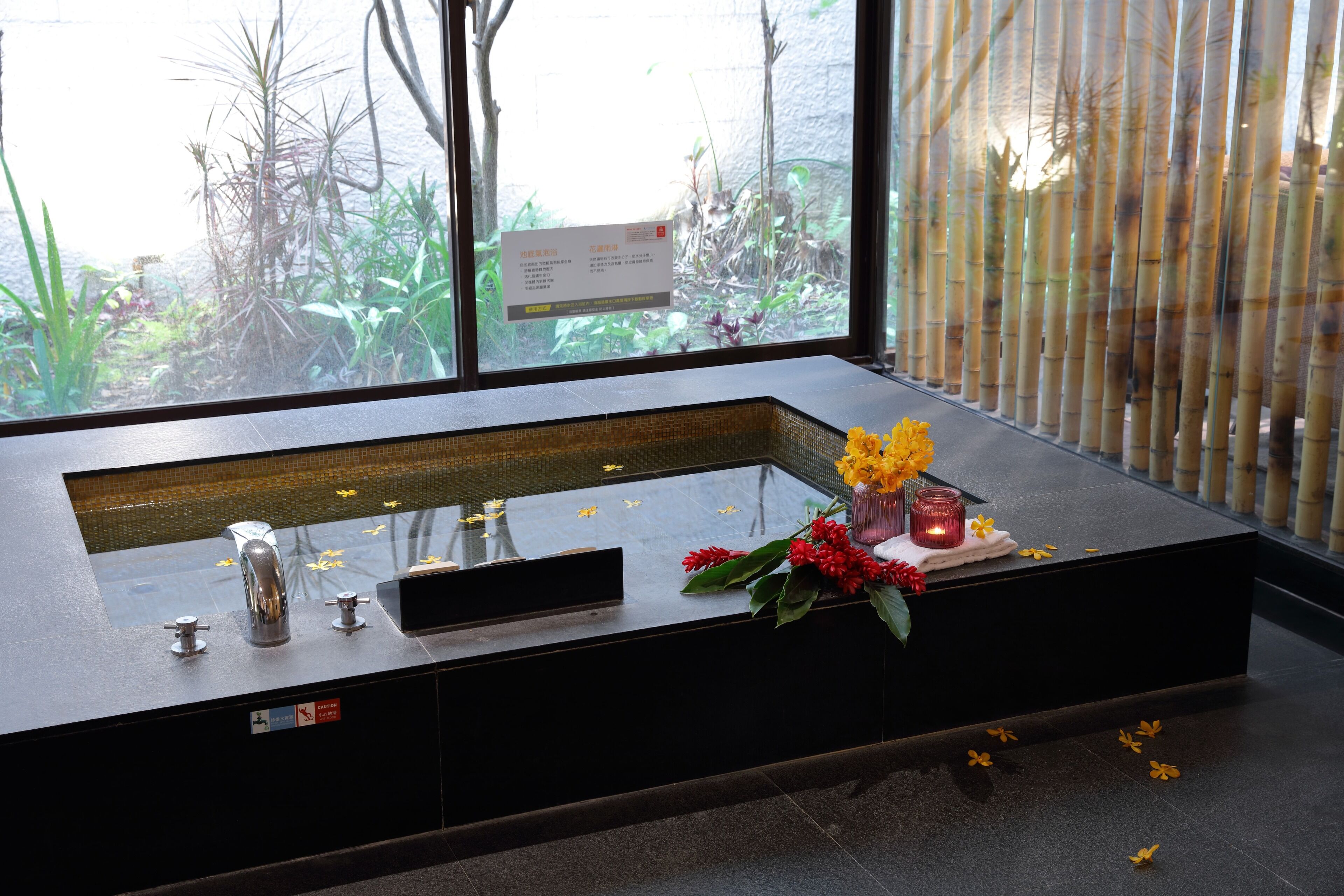 A modern bathroom with a large sink, a mirror, and a window with a view of greenery.