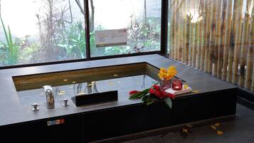 A modern bathroom with a large sink, a mirror, and a window with a view of greenery.