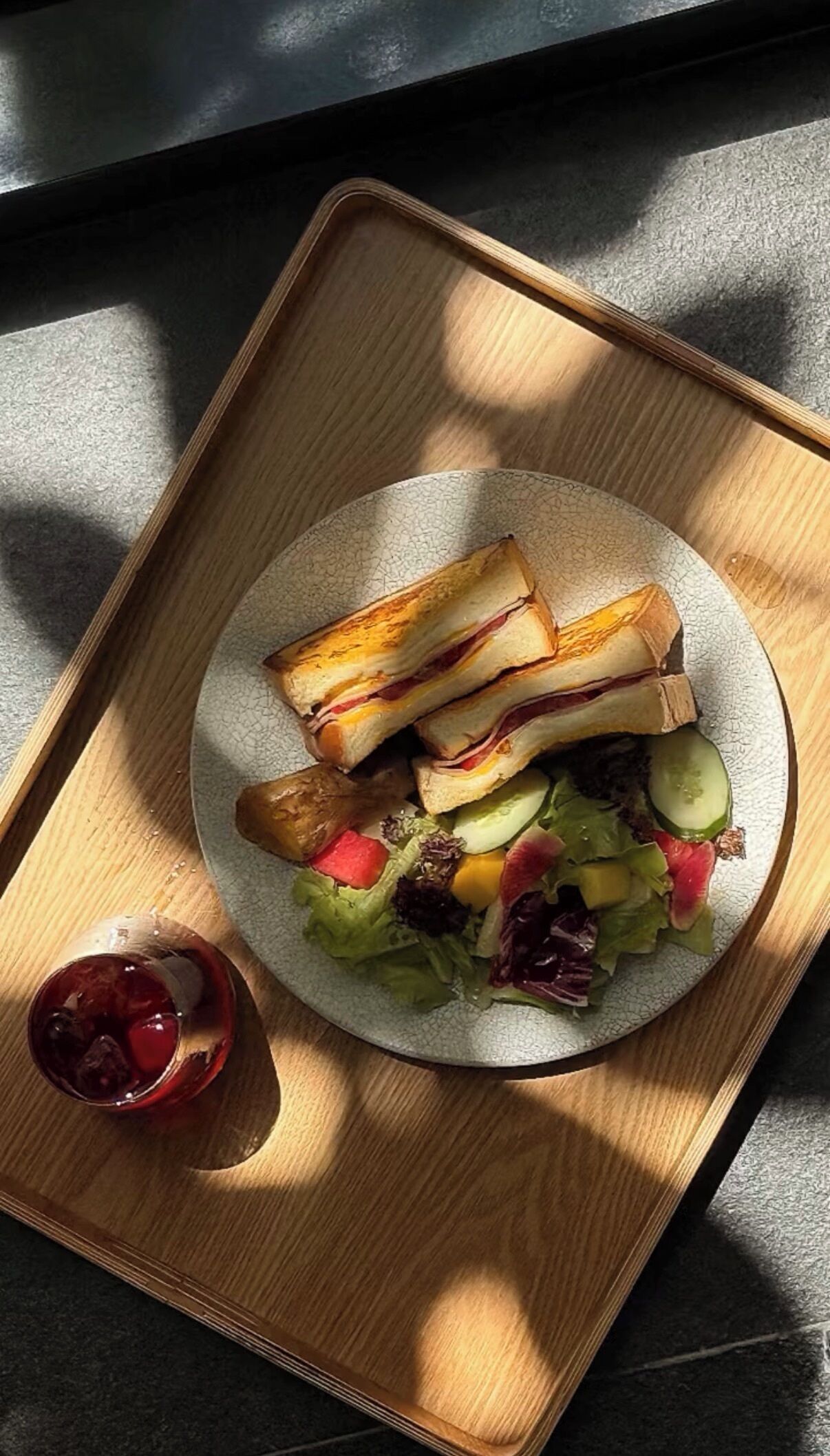 A plate of sandwiches and salad on a wooden tray.