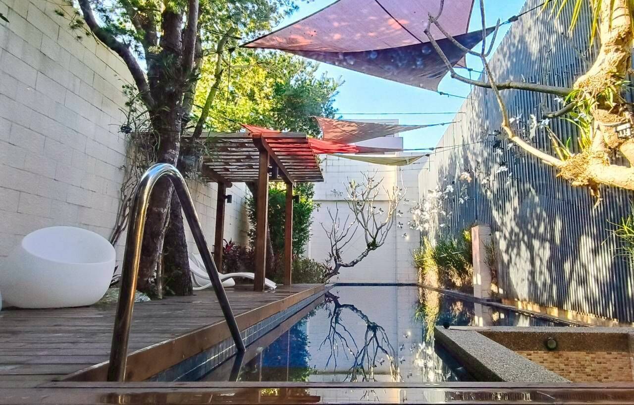 A pool area with a wooden deck, a white bowl, and a pergola with a red roof.