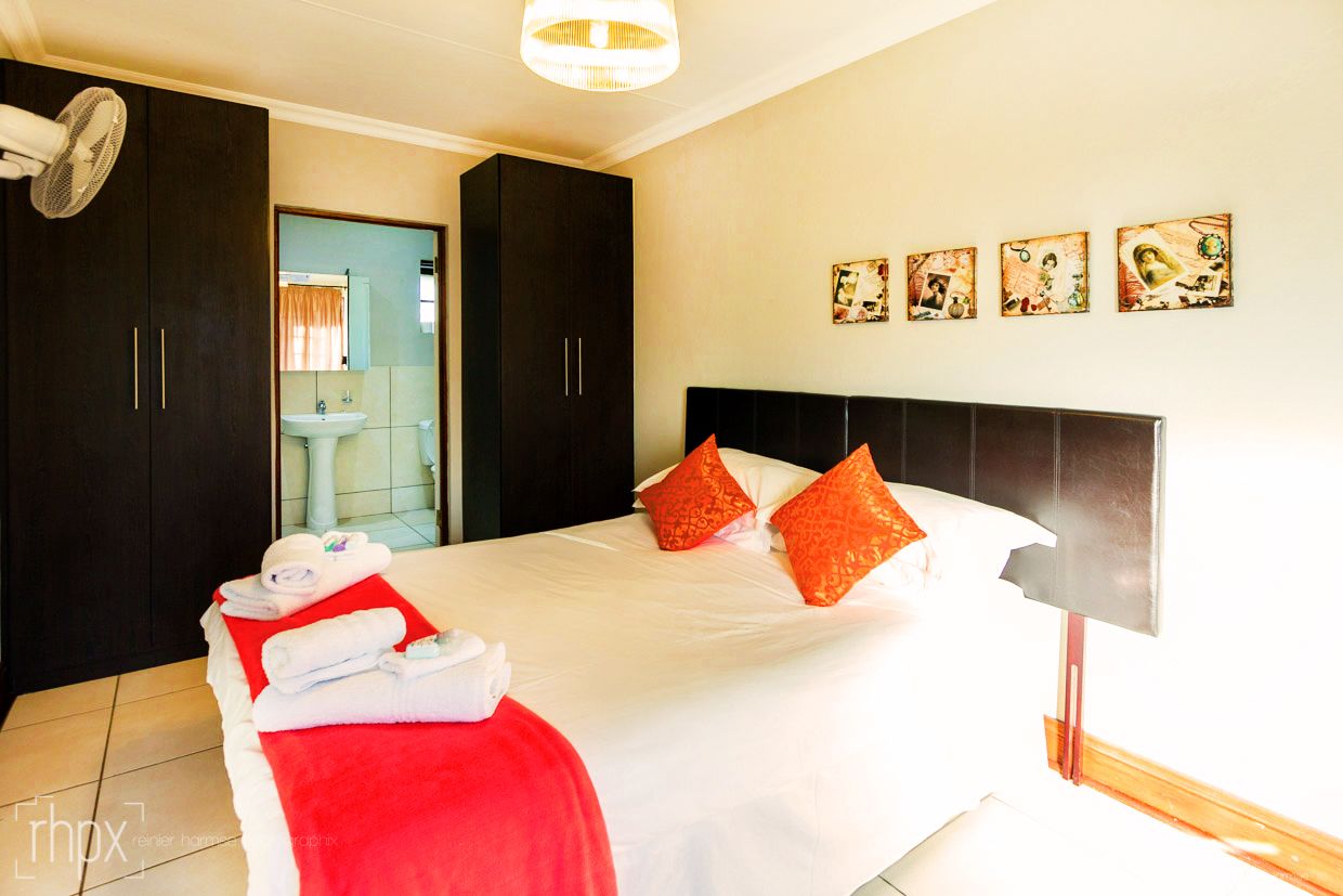 A hotel room with a bed, a large wardrobe, a bathroom visible through an open door, and wall art.