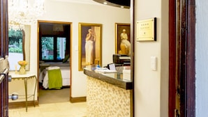 Een hotel receptie met een receptiebalie, een kroonluchter en ingelijste kunst aan de muur.