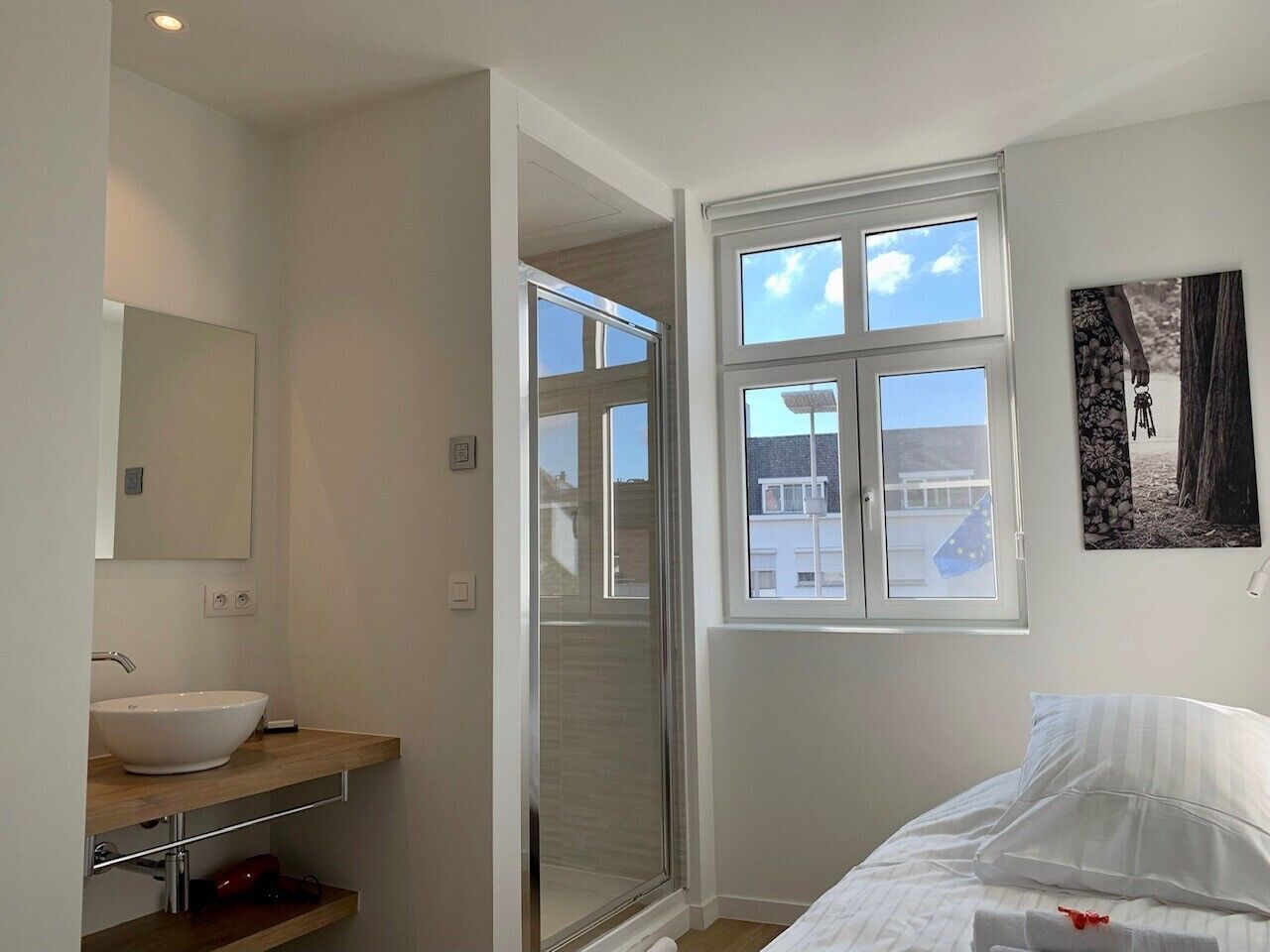 Une salle de bain moderne avec une grande fenêtre, un lavabo et un lit.