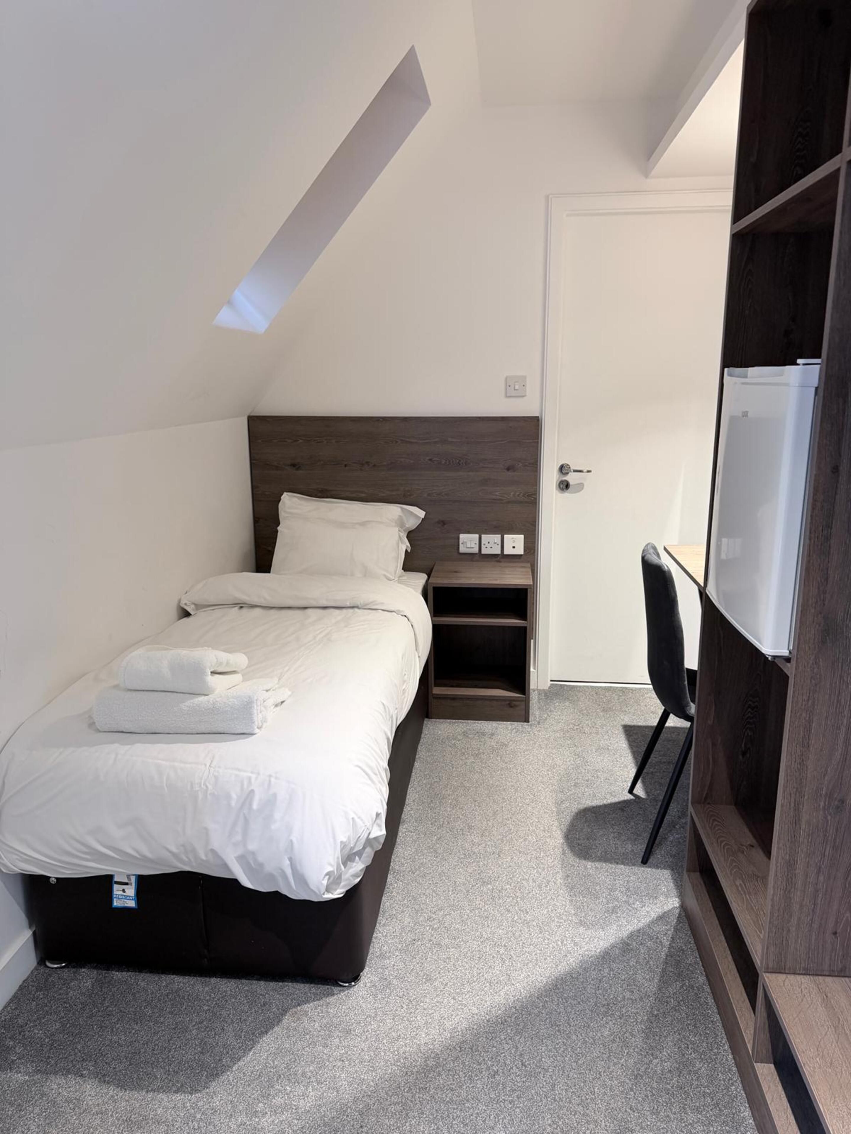 Un dormitorio con cama, escritorio y armario.