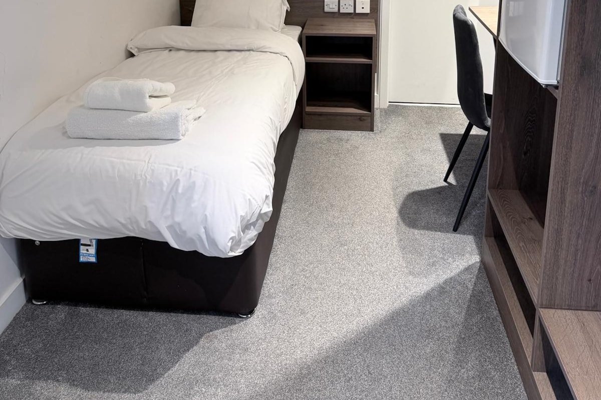 Een slaapkamer met een bed, een bureau en een kledingkast.