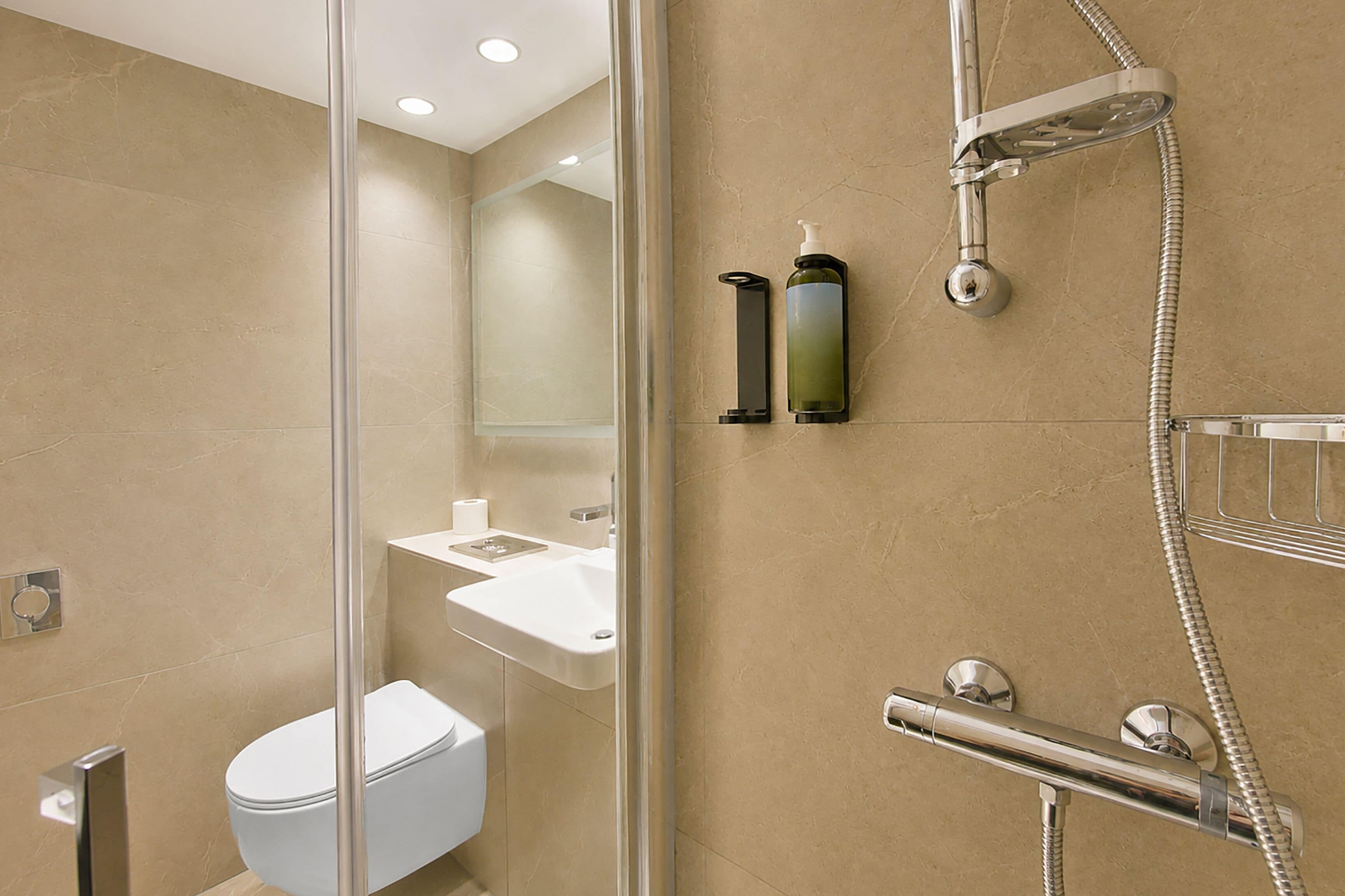 A modern bathroom with a glass partition, a toilet, a sink, and a shower.