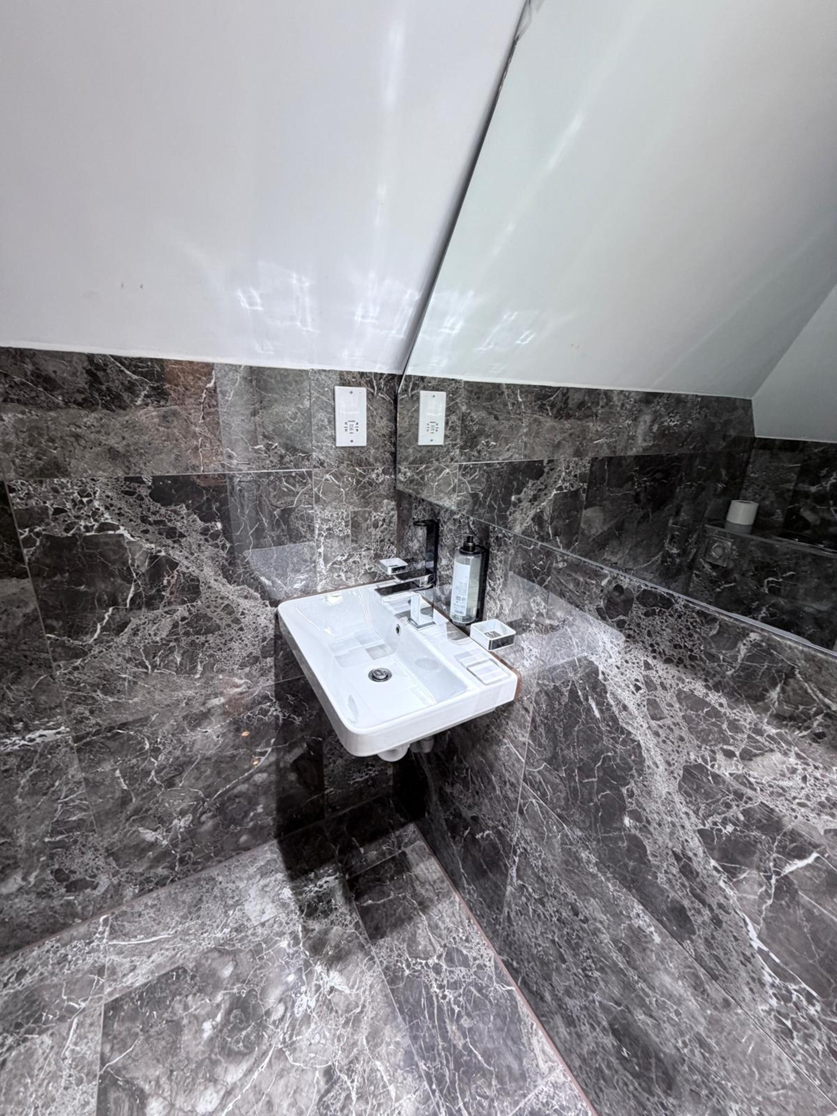 A bathroom with a marble sink, a mirror, and a towel rack.