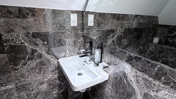 Un baño con lavamanos de mármol, un espejo y un perchero para toallas.