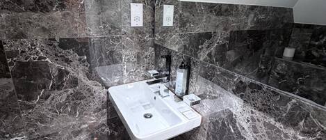 A bathroom with a marble sink, a mirror, and a towel rack.