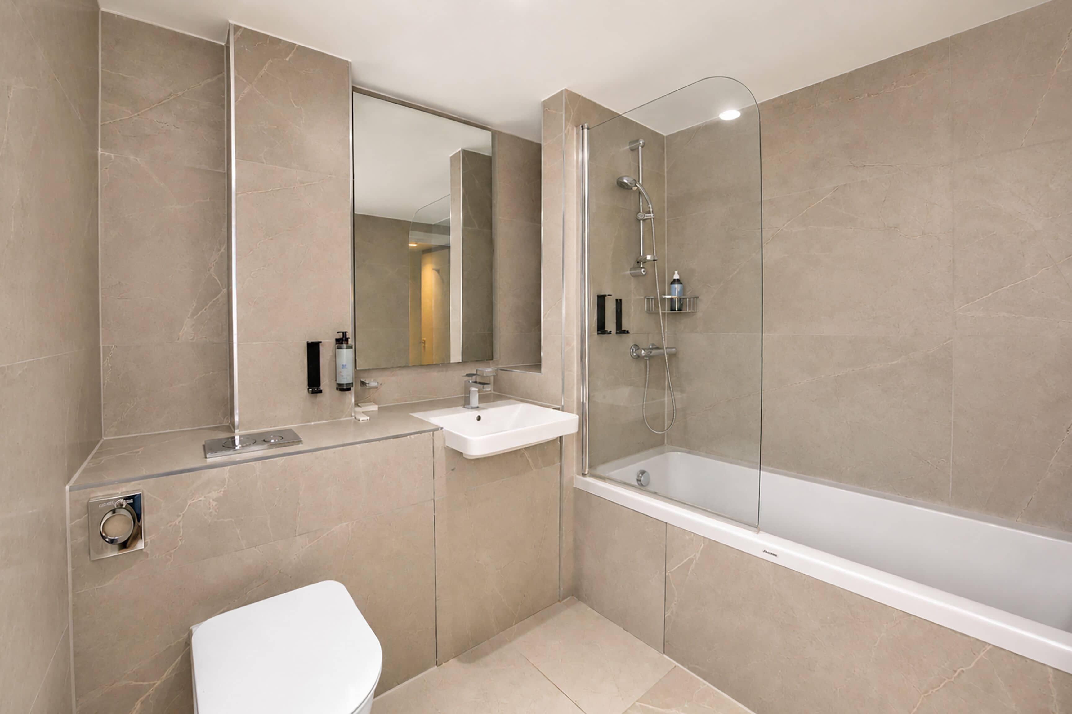 A modern bathroom with a glass-enclosed shower, a white sink, and a toilet.