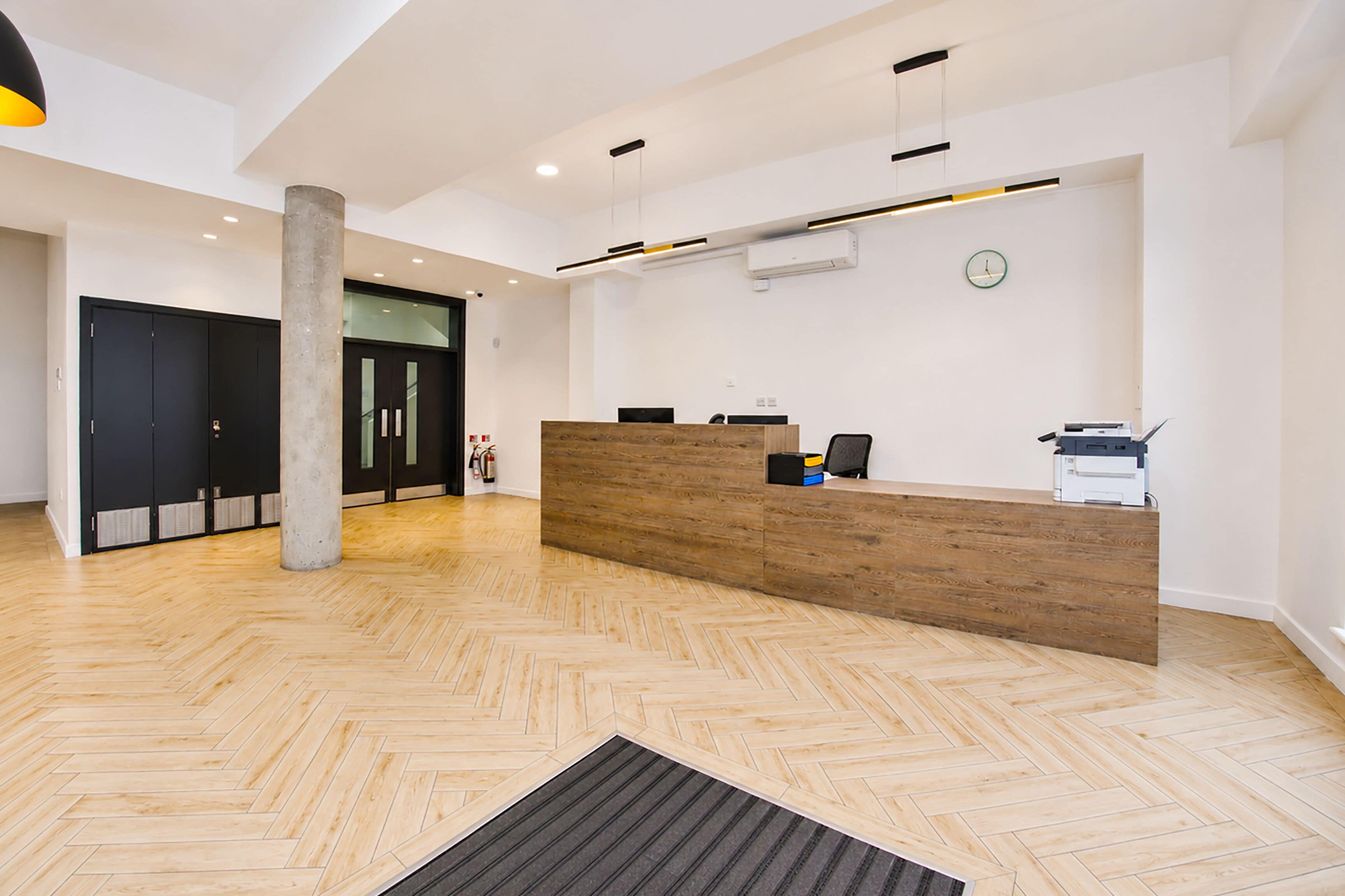 A reception area with a wooden reception desk, a clock on the wall, and a fire extinguisher.