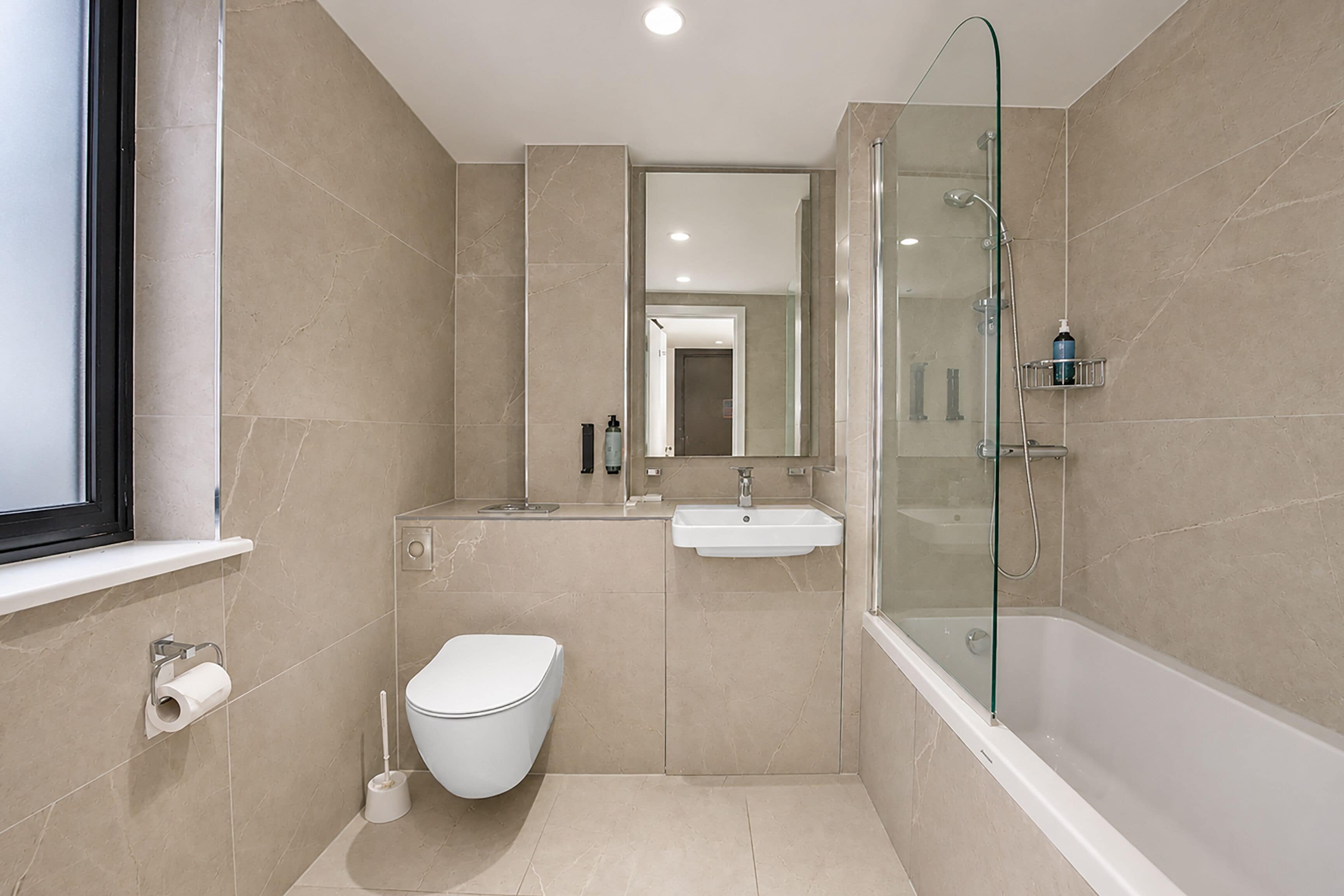 A modern bathroom with a toilet, sink, and glass-enclosed shower.