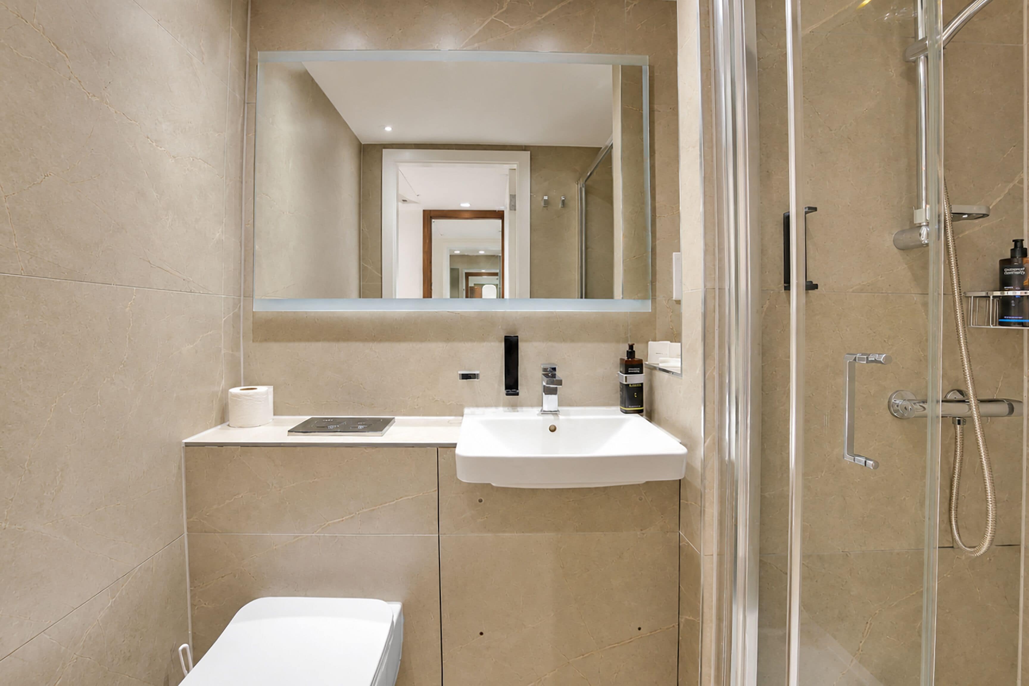 Een badkamer met wastafel, spiegel, toilet en douche.