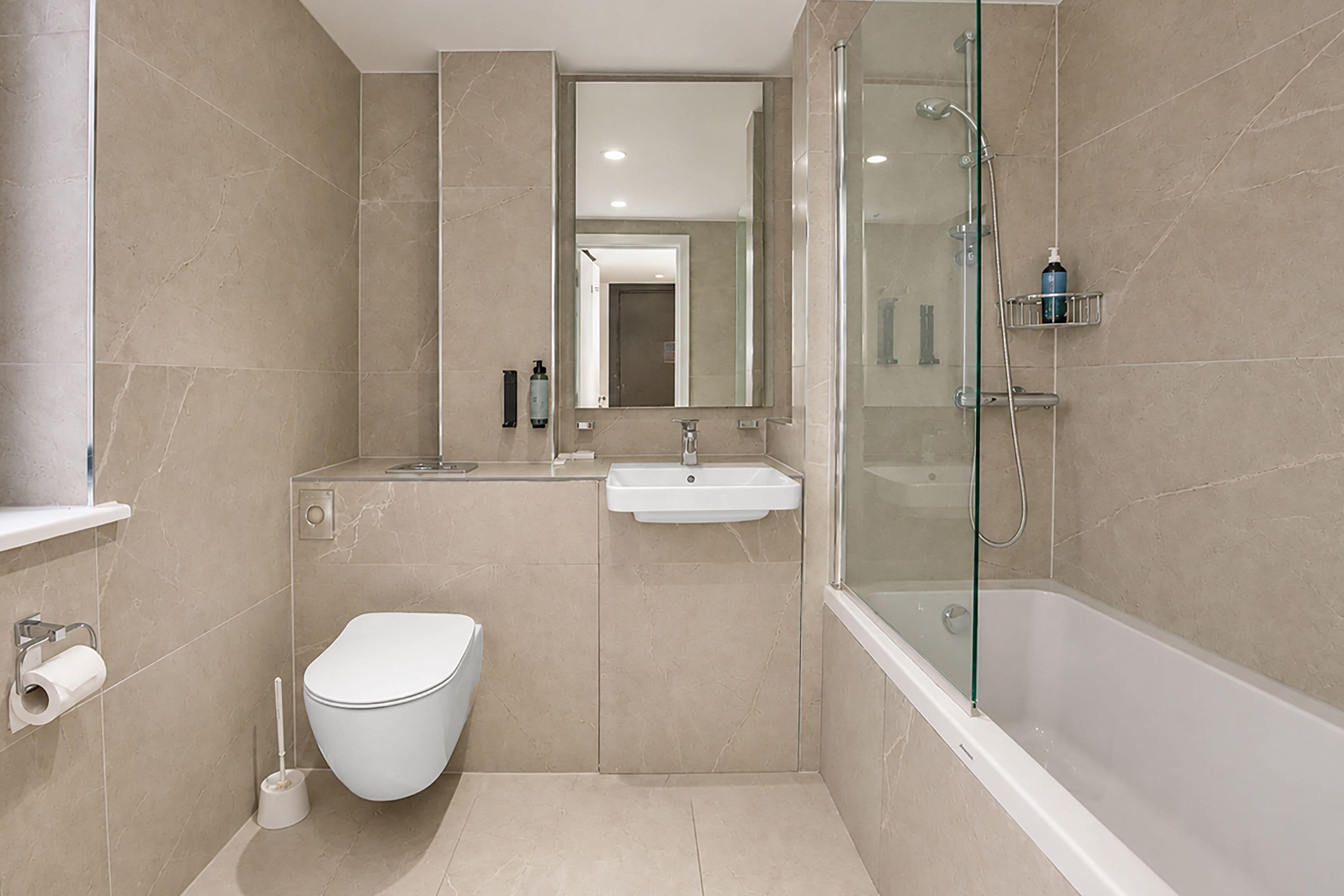 A modern bathroom with a toilet, sink, and glass-enclosed shower.