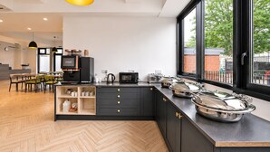 Una cocina moderna con suelo de espiga, armarios negros y un amplio ventanal con vistas a un muro de ladrillo.