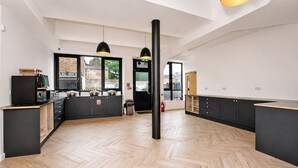 Cocina moderna con armarios negros, suelo de herringbone de madera e iluminación colgante.