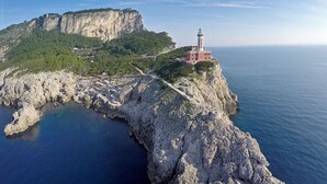 A coastal cliff with a lighthouse, rocky terrain, and a clear view of the sea. - Fortino Bed & Breakfast (Capri)