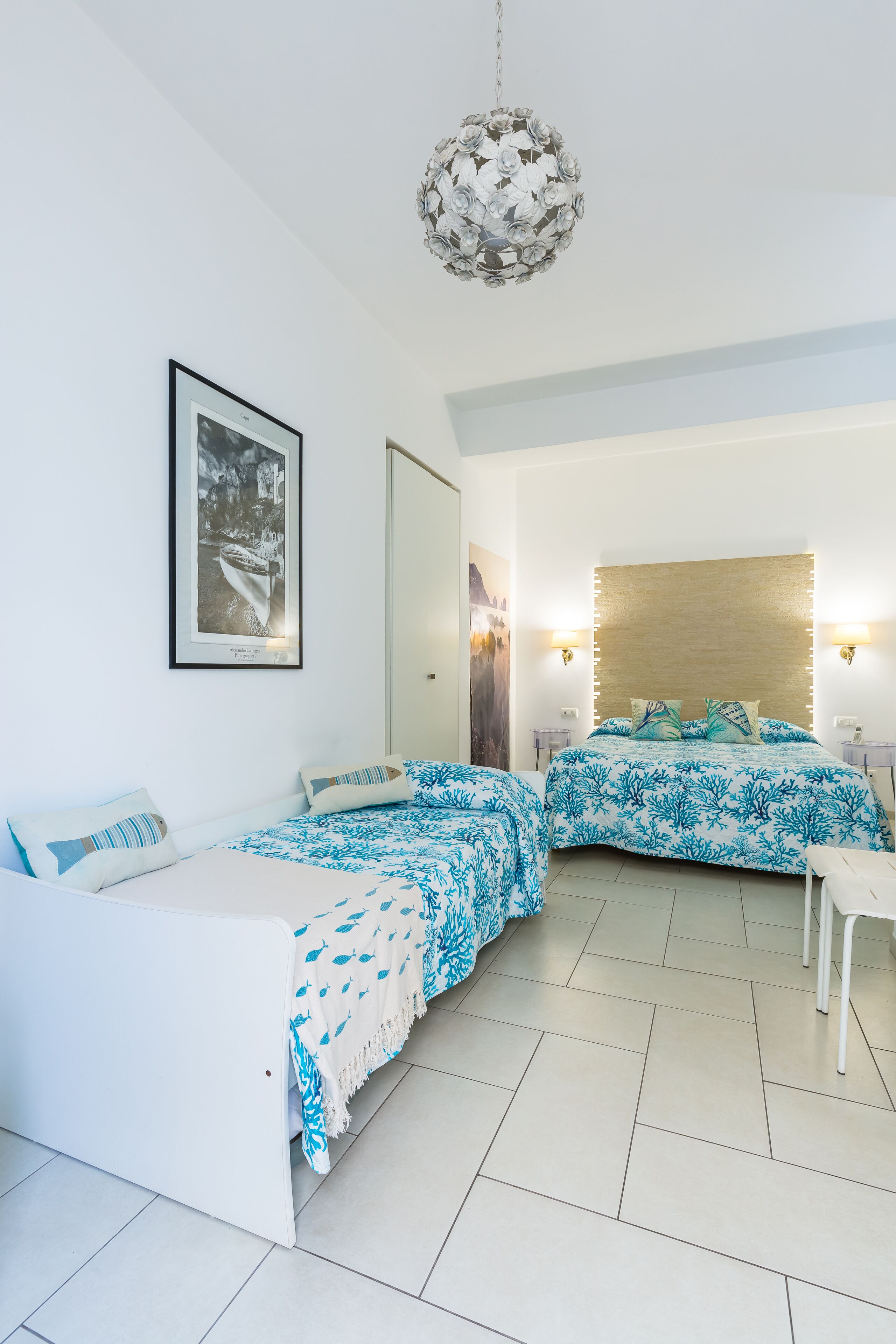 A modern bedroom with two beds, a large mirror, and a chandelier.
