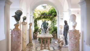 Un sendero clásico de jardín con estatuas y una mesa central.