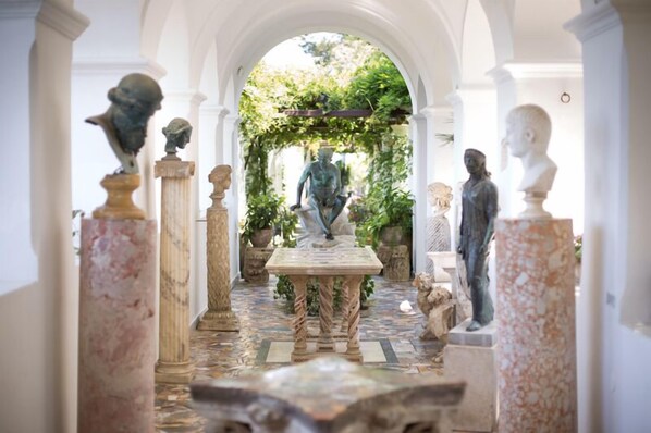 Un sendero clásico de jardín con estatuas y una mesa central.