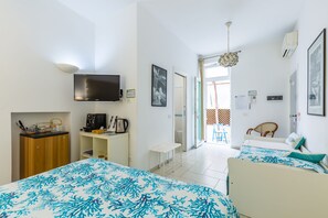 Ein Hotelzimmer mit zwei Betten, einem Schreibtisch, einem Fernseher und einer Küchenzeile.