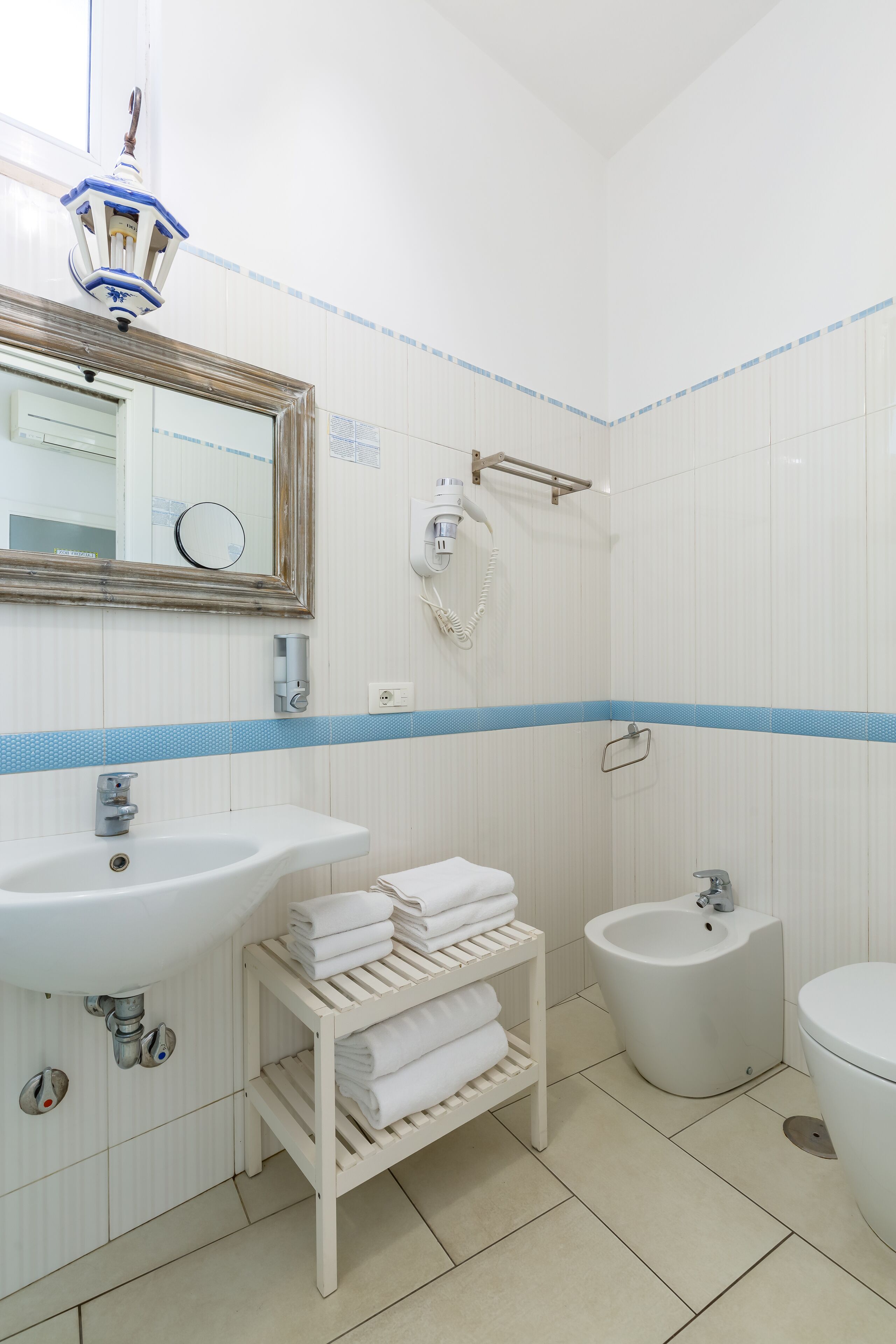 A bathroom with a sink, bidet, toilet, and a towel rack.
