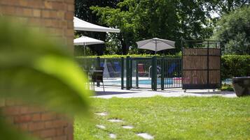 Een seizoensgebonden buitenzwembad, ligstoelen bij het zwembad