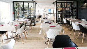 Un restaurante con varias mesas, sillas y una vitrina de vinos.