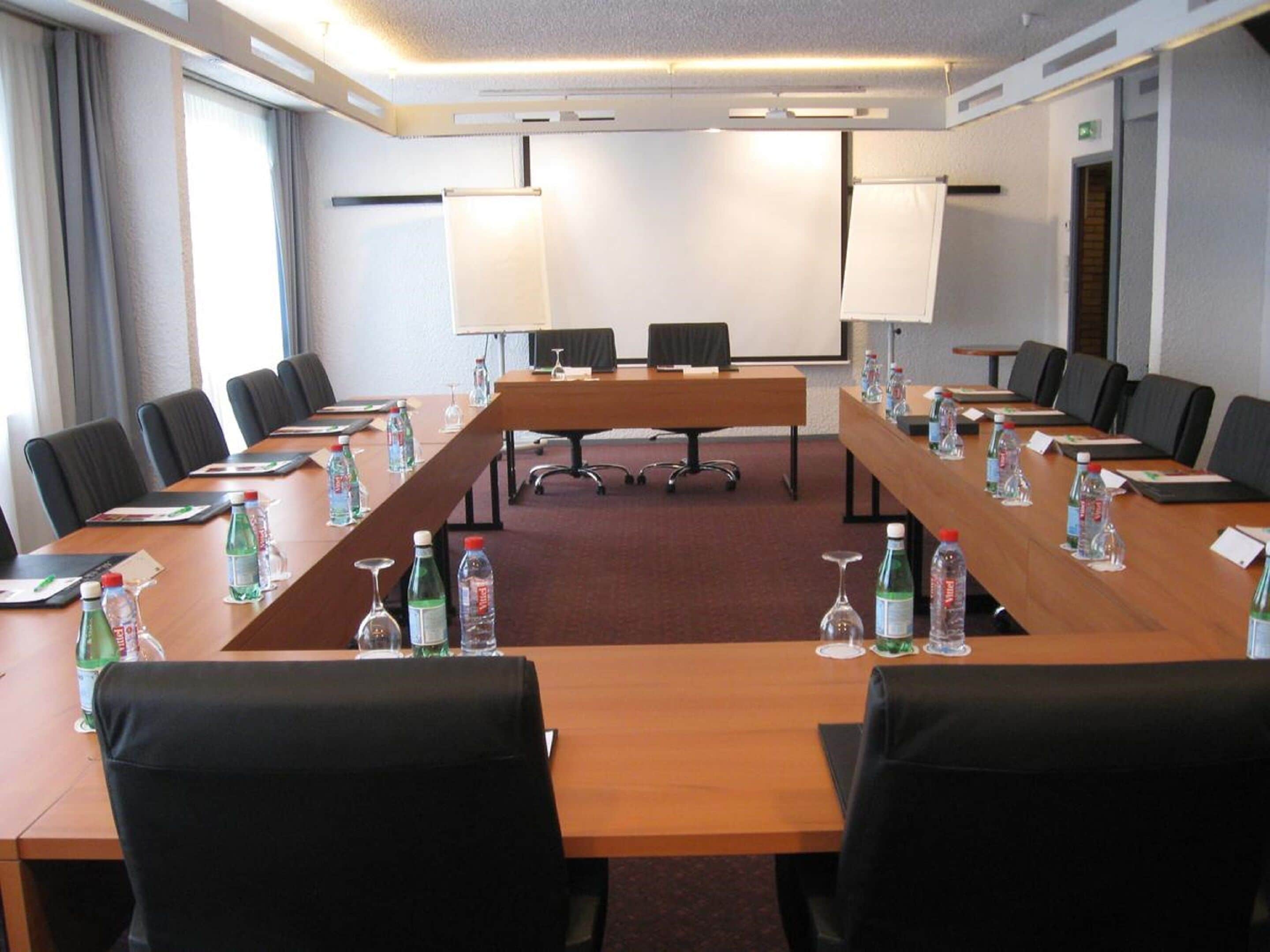 A conference room with a long table, chairs, water bottles, and nameplates.
