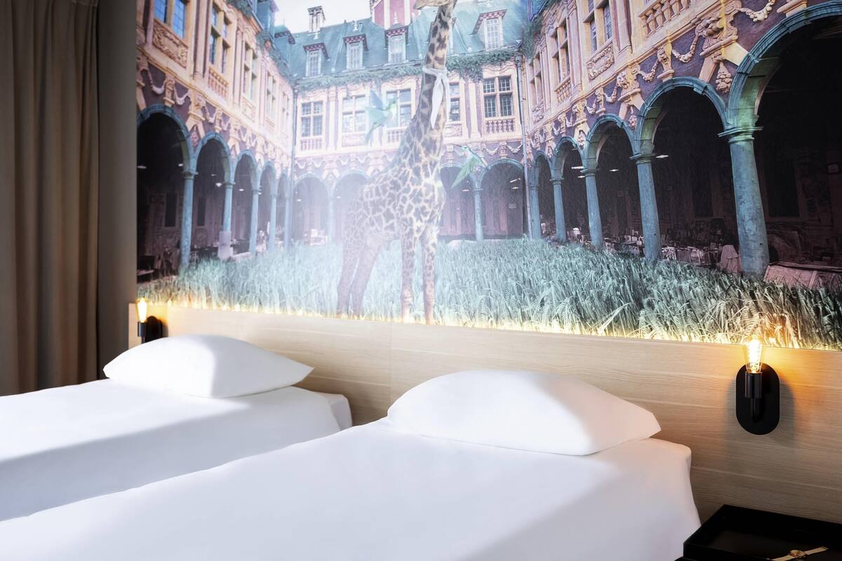 A hotel room with a large projection of a historic building, a giraffe, and a field of tall grass.