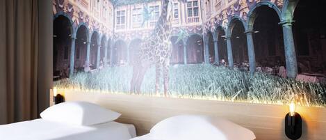 A hotel room with a large projection of a historic building, a giraffe, and a field of tall grass.