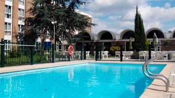 Relax by the rectangular pool surrounded by lounge chairs and umbrellas.