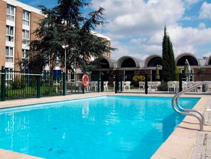 En säsongsöppen utomhuspool och solstolar