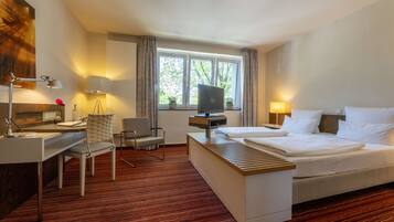 A hotel room with a bed, desk, chair, TV, and windows.