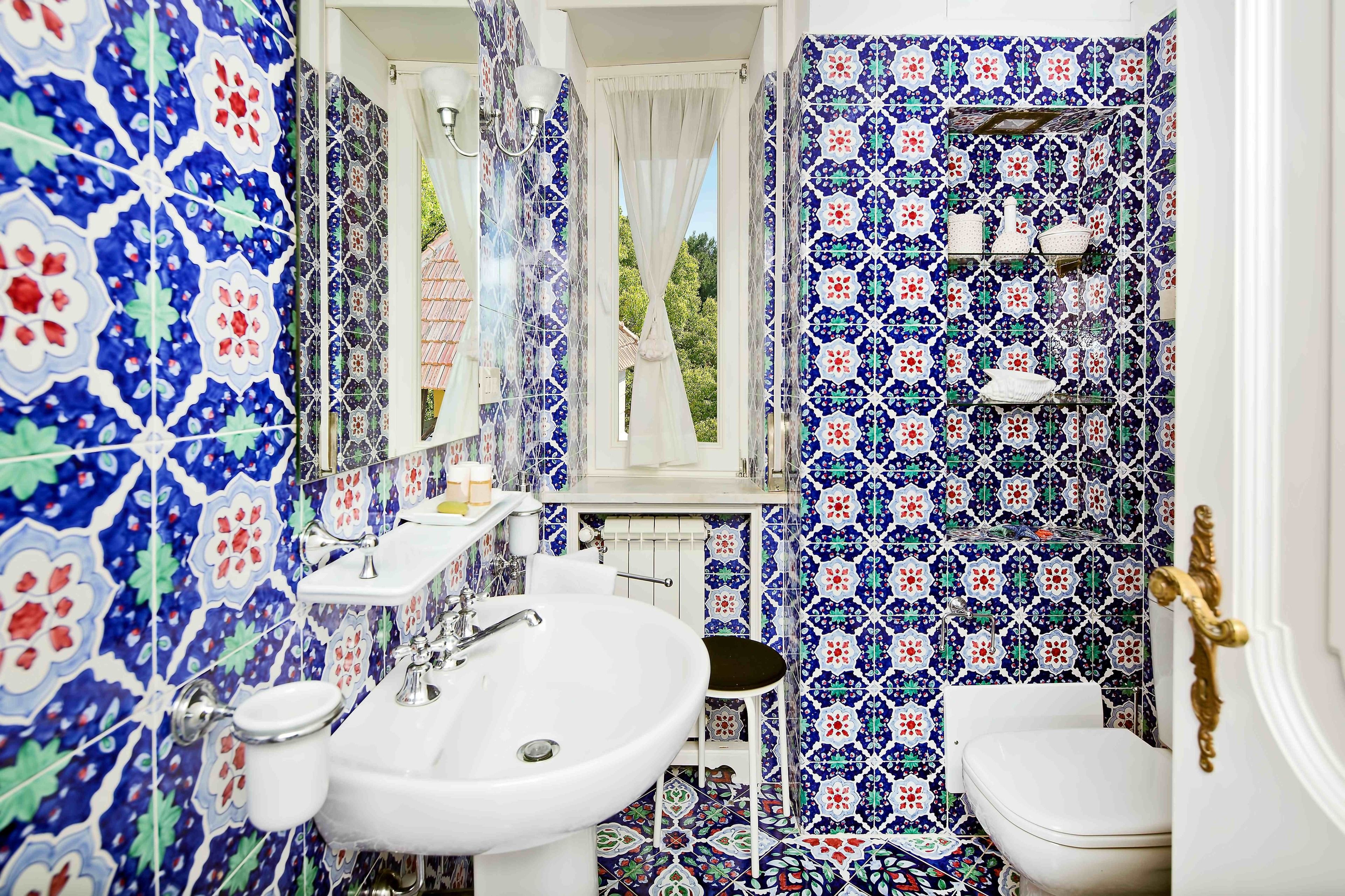 A bathroom with a white sink, toilet, and a window with a view of greenery.