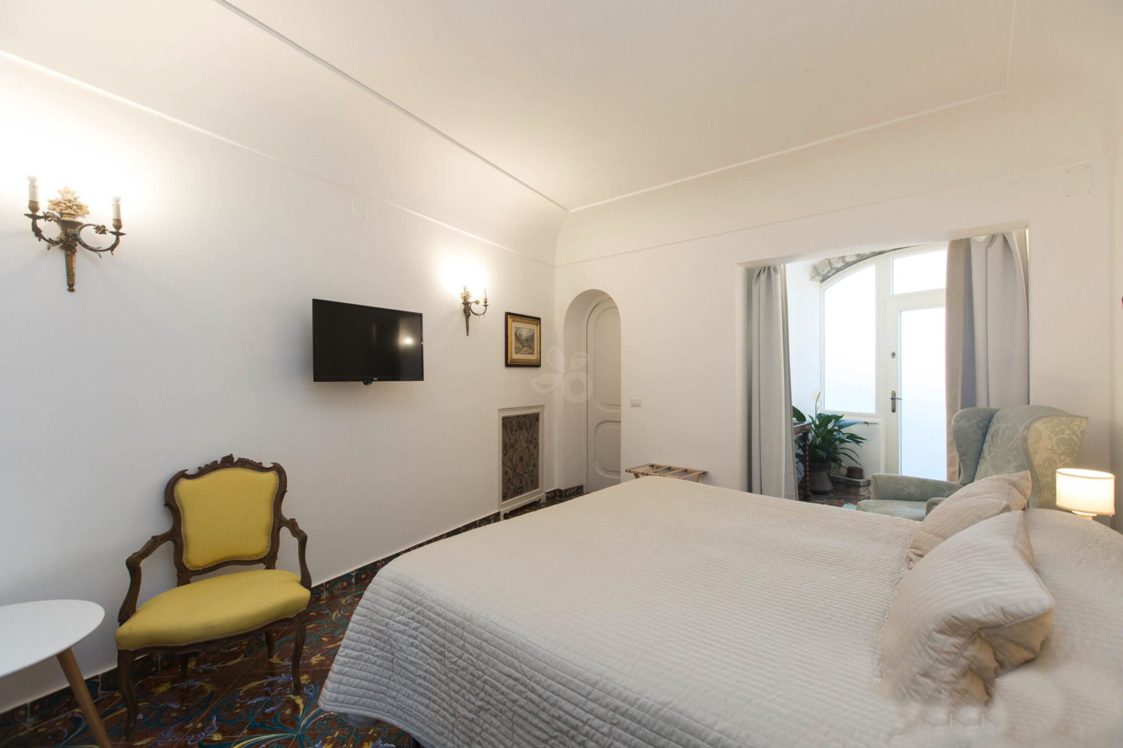 Une chambre d’hôtel avec un grand lit, une télévision, une chaise et une petite table.