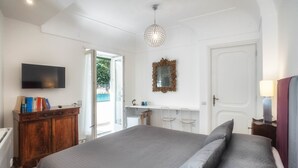 Un dormitorio con una cama, televisor, cómoda de madera, espejo y puerta.