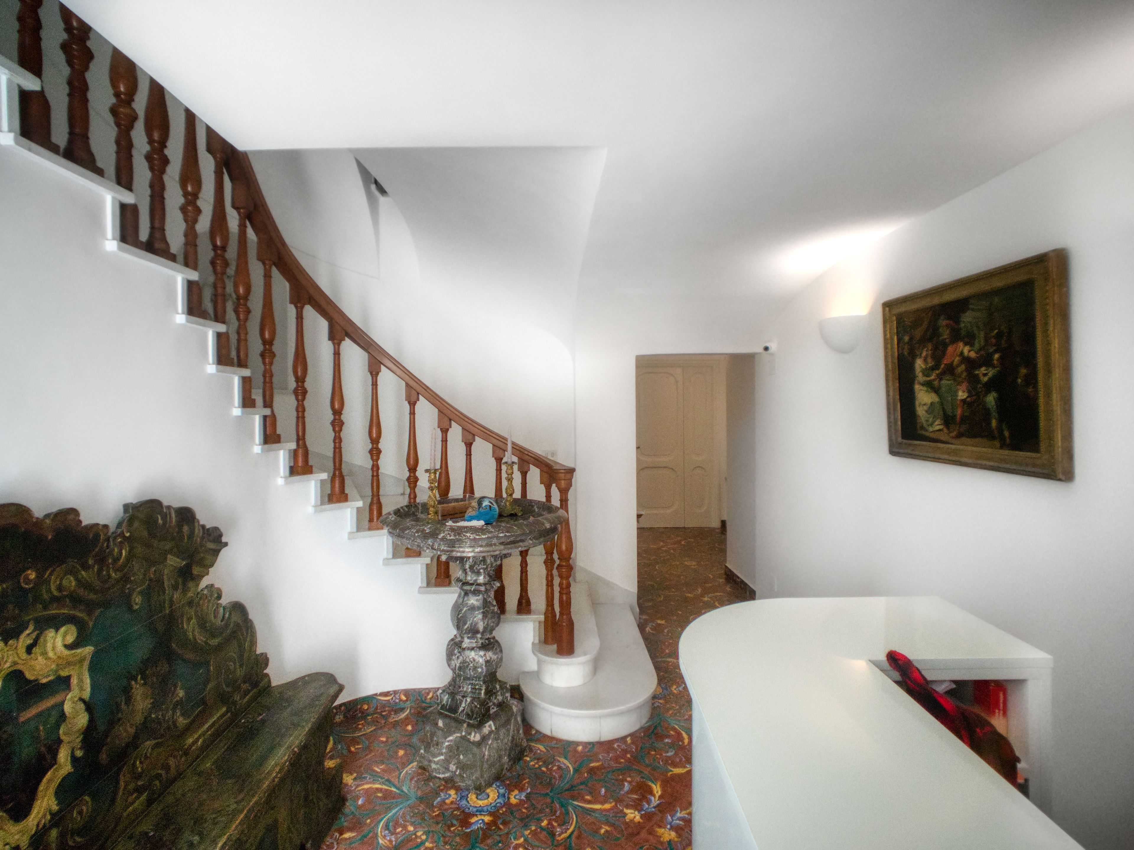 A staircase with wooden balusters, a marble fountain, and a patterned carpet.