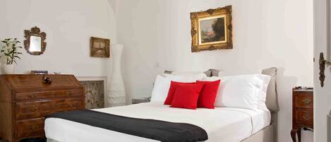 A bedroom with a large bed, a wooden dresser, a mirror, and two framed pictures on the wall.
