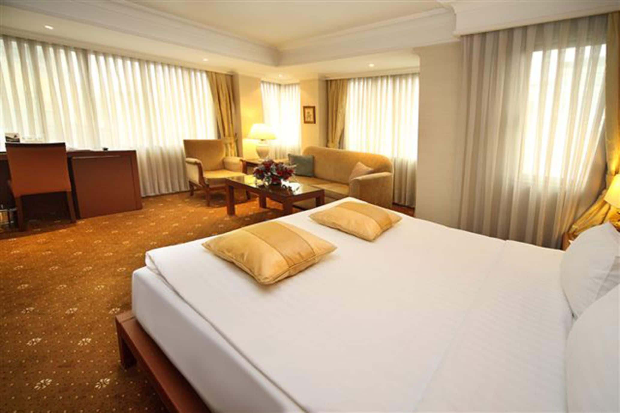 A hotel room with a large bed, two chairs, a desk, and a coffee table.
