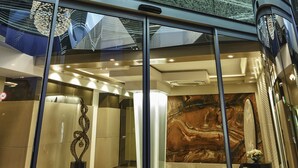 Un intérieur moderne avec un plafond en verre, un mur de marbre et une sculpture métallique décorative.