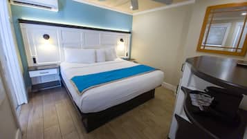 Una habitación de hotel con cama, mesitas de noche, un espejo y un ventilador de techo.