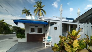 A youth hostel with a white exterior, a blue awning, and a white picket fence.
