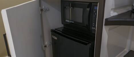 Una kitchenette compacta equipada con un refrigerador integrado, un microondas y un horno pequeño.