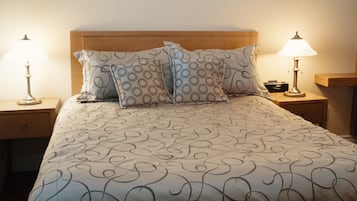 A neatly made bed with a patterned bedspread, two decorative pillows, and two bedside lamps on wooden nightstands.